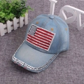 Detail of light blue denim cap featuring American flag rhinestone patch and studded brim - One Size / Light Denim