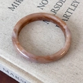 Close-up of irregular resin bangle featuring marble patterns on a linen book cover - Tea Color Round Loop (25835A)