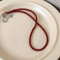 Detail of red beaded necklace with silver lobster clasp on a ceramic tray - 4mm / 4mm Red Necklace