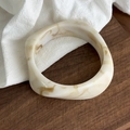Detail of chunky resin bangle with cream and brown marble pattern on wooden surface - Creamy White Geometric Style (26989)