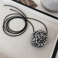 Vue détaillée de la rose en tissu léopard sur un long collier ras du cou à cordon noir - Base Blanche Léopard Noir