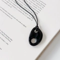 Detalle de un colgante de resina negra brillante con diseño de doble agujero en un libro - Negro