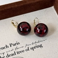 Detailed macro view of leopard print resin ball earrings with elegant gold leverback hooks - Dark Red Leopard
