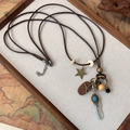 Dettaglio di una collana etnica vintage con piuma metallica e ciondoli in perle di legno - Collana a Due Strati con Piume (26001A)