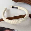 Close-up of knit headband texture in cream color featuring a handmade textile label - White