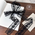Detail of elegant black lace ribbon with floral embroidery tied into a large bow - 2m / Black Vine