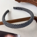 Close-up of dark grey knitted headband showing handmade label and diagonal wool texture - Gray