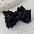 Dettaglio del fermaglio a fiocco nero in tessuto opaco su uno sfondo in stile minimalista - Nero