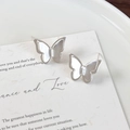 Primer plano de pendientes de mariposa plateados con textura en una tarjeta de regalo - Estilo Plateado