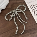 Close-up of handmade silver beaded bow charm on a minimalist dark wood surface - 26043G 3-Loop Silver Beaded Bow