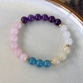 Detail eines bunten Kristall-Perlenarmbands mit lila, rosa und blauen Steinen und Goldperlen - Weiß Violett Rosa