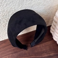 Detail of a thick padded black velvet headband resting on a rustic wooden tabletop - Black