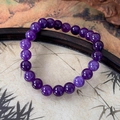 Detailed close-up of natural purple amethyst beads on a zen-style dark bamboo background - Purple
