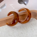 Detailed close-up of retro caramel C-shape resin hoop earrings with tortoiseshell pattern - Amber