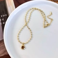 Detail of tiger eye pendant on beaded gold chain with lobster clasp on white ceramic plate - Rice Bead Chain Round Pendant Style (26129B)