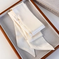 Detail of elegant cream satin skinny scarf folded on a display tray with silky texture - White (26183A)