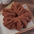 Detailed macro view of a large brown teddy fleece scrunchie on a wooden tray with soft texture - Brown