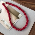 Dettaglio macro delle perle di vetro rosso vivace e della chiusura dorata della collana - Collana 10mm