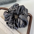Close-up of silver beaded bow on shiny metallic scrunchie with satin texture details - Dark Black (26205B)