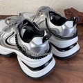 Close-up of stylish double-layer pearl and silver chain accessories on chunky sneakers - Black