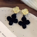 Detail von französischen Samtblumen-Ohrringen auf Keramikteller mit eleganter Goldstruktur - Schwarze Blume