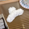 Close-up of a large white plush faux fur shark hair claw clip on a decorative tray - White