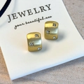 Detailopname van geborstelde gouden oorbellen met zirkonia op witte displaykaart - Goud Stijl