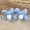 Dettaglio degli orecchini a fiocco in maglia blu con morbidi pompon di peluche bianchi - Fiocco Blu (26325C) / Blu