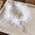 Dettaglio choker di piume bianche con pendente in cristallo su vassoio in lino beige - Bianco