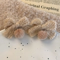 Détail de boucles d'oreilles nœuds tricotés beige avec pompons en fausse fourrure douce - Café
