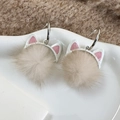 Nahaufnahme von Katzenohr-Pom-Pom-Ohrringen auf einem Keramiktablett mit Winter-Vibe - Beige Stil