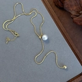 Macro shot of gold snake chain with white pearl pendant and adjustable metal bead detail - Golden Large Pearl Long Chain Lariat Style (23179A)