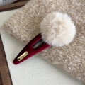 Detailaufnahme einer roten Samt-Haarklammer mit Plüsch-Pompon und Handarbeit-Etikett - Kaffee Bommel Burgund Klammer