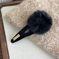 Détail de la pince à cheveux pompon noir avec plaque dorée sur tricot beige - Pompon Noir Pince Noire