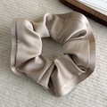 Detail of a champagne silk satin scrunchie with a soft ruffled edge on a knit background - Apricot