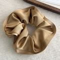 Close-up of champagne satin scrunchie featuring elegant ruffles and smooth silky texture - Brown