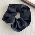 Detail of a black satin scrunchie with elegant ruffled edges and glossy texture - Black