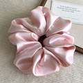 Close-up of a soft pink satin scrunchie with glossy texture and elegant folds - Pink