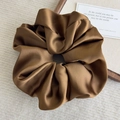 Macro shot of brown satin silk scrunchie with glossy texture on warm knitted background - Coffee