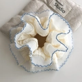 Detailaufnahme von cremefarbenem Spitzen-Haargummi mit blauer Borte und Faltenstruktur - Blaue Spitzenkante