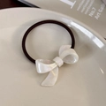Dettaglio dell'elegante elastico per capelli con fiocco in acetato bianco perlato su un piatto - Bianco Iridescente