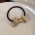 Dettaglio di elastico per capelli con fiocco in acetato marmorizzato beige e nero - Caffè Cremoso
