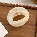 Detailed top view of a cream translucent resin hair claw clip on a wooden tray - Oval Style / Beige