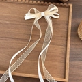 Détail d'un nœud en satin blanc et dentelle beige sur plateau en bois avec longs rubans - Nœud Beige
