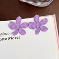 Dettaglio di orecchini a fiore viola opaco su un libro, mostrando la trama dei petali - Fiore Opaco a Cinque Petali (19958)