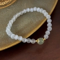 Nahaufnahme von Katzenaugen-Perlenarmband mit grünem Edelstein und goldenem Spacer - Weiß und Hellgrün