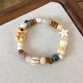 Detalle de pulsera de cuentas con oso de cerámica, estrella y dijes de hueso en lino - Estilo Koala (25200C)