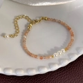 Detail of sunstone beaded bracelet with white pearls and gold metal spacers on ceramic tray - Champagne Beads (25227C)