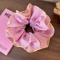 Détail d'un chouchou à carreaux roses avec bords festonnés jaunes sur table en bois - Rose à Carreaux