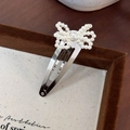 Detailed close-up of a pearl bow hair clip with silver metal BB clip base on a fabric board - Small Bowknot (25329A) / Silver